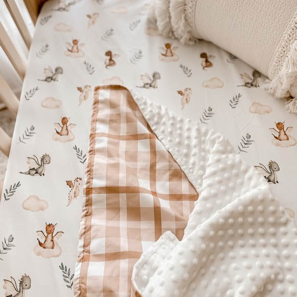 Close image of a minky pram blanket laid over a 100% cotton sheet with dragon prints