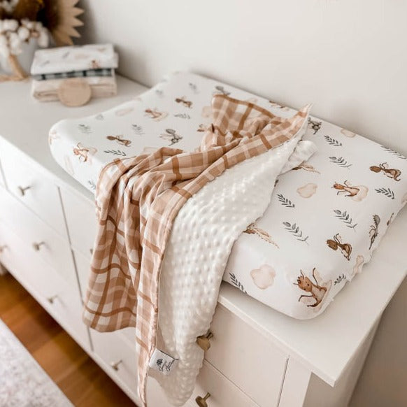 A high perspective of a minky stroller blanket draped over a change table in a modern nursery setting.