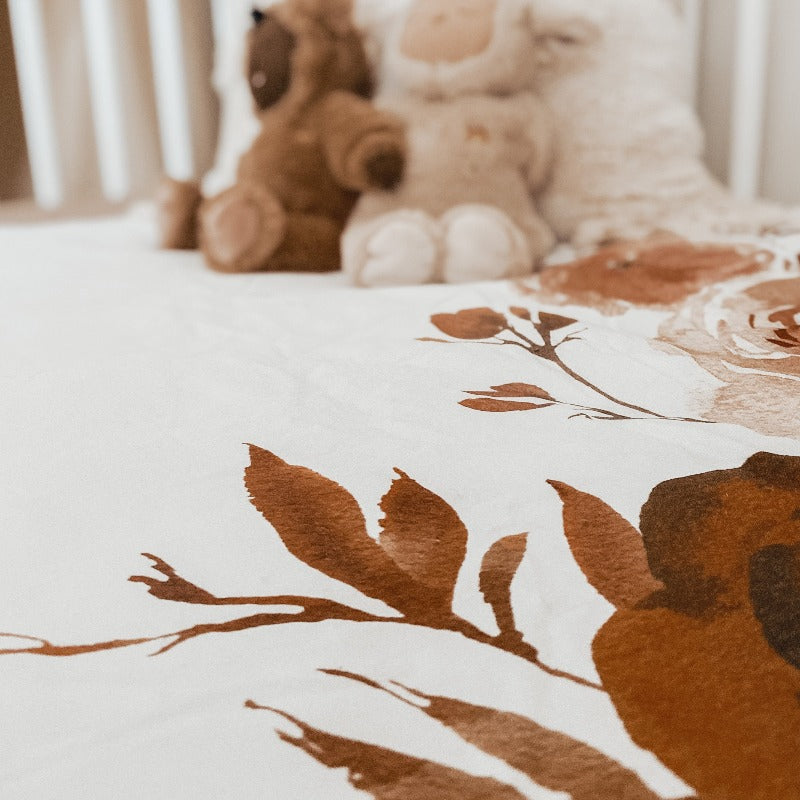 Low angel of two plush toys sitting on a quilt in a white pine crib