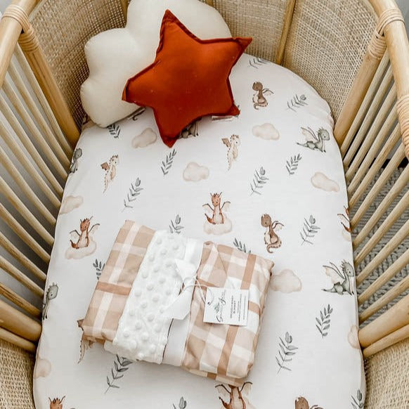 Earthy plaid dimple dot minky presented on top of a white bassinet sheet in a rattan bassinet