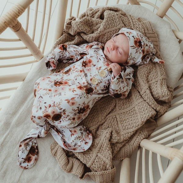 A baby wearing a floral print knotted gown