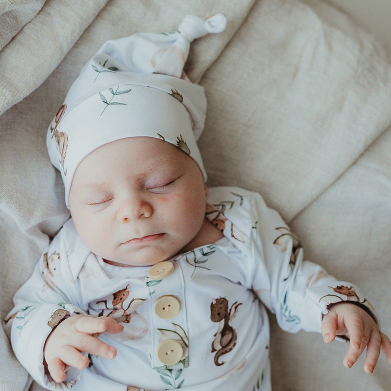 Close up of a baby while he is wearing a dragon print beanie 