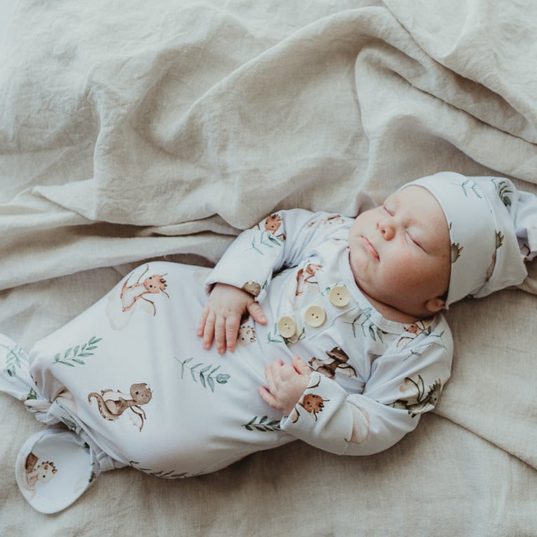 Chubby little dude laying on a cotton throw rug wearing a knotted gown with dragon prints