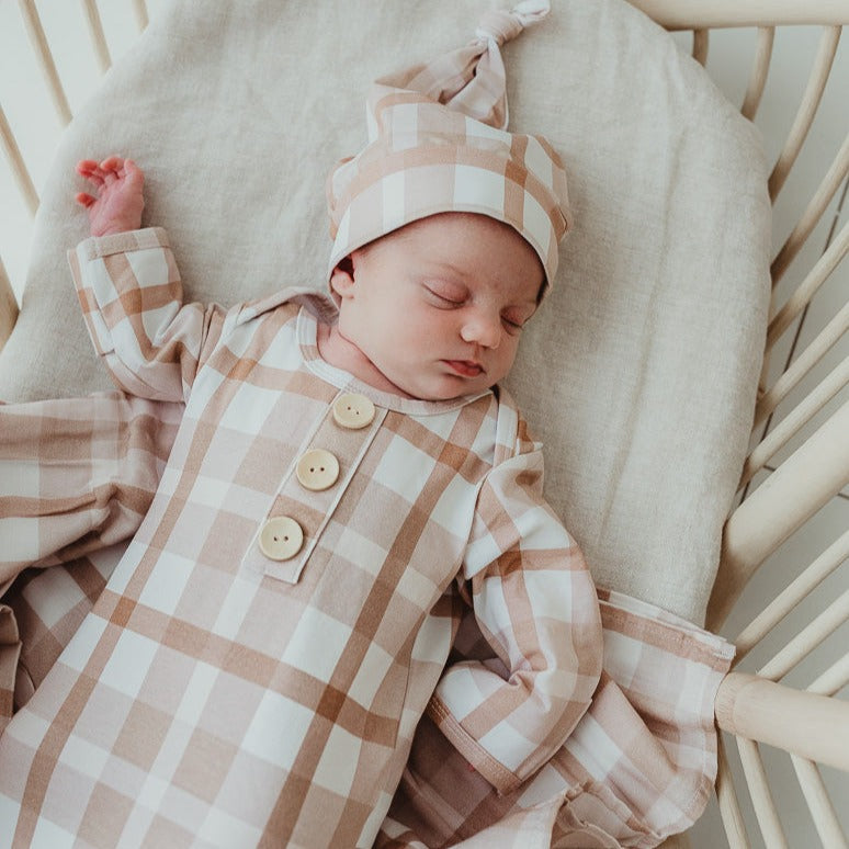 Tiny little baby wearing a knotted gown in soft brown and a matching beanie