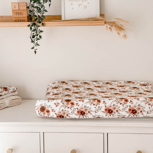 White change table with floral burp cloths on one side and a change pad covered by a 100% cotton cover 