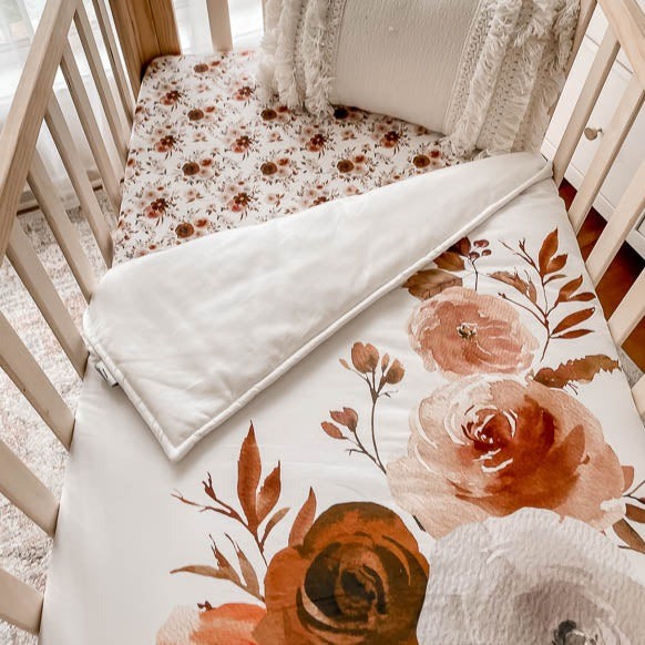 Over head shot of a pine crib depicting a floral crib quit made from 100% cotton