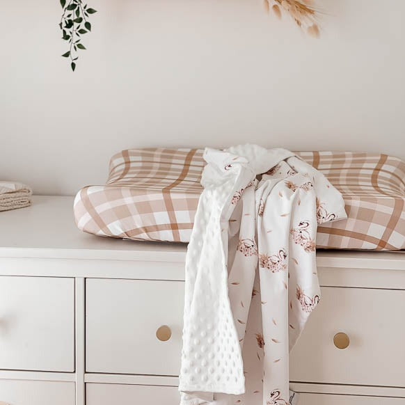 White minky stroller blanket laying on top of a change pad 